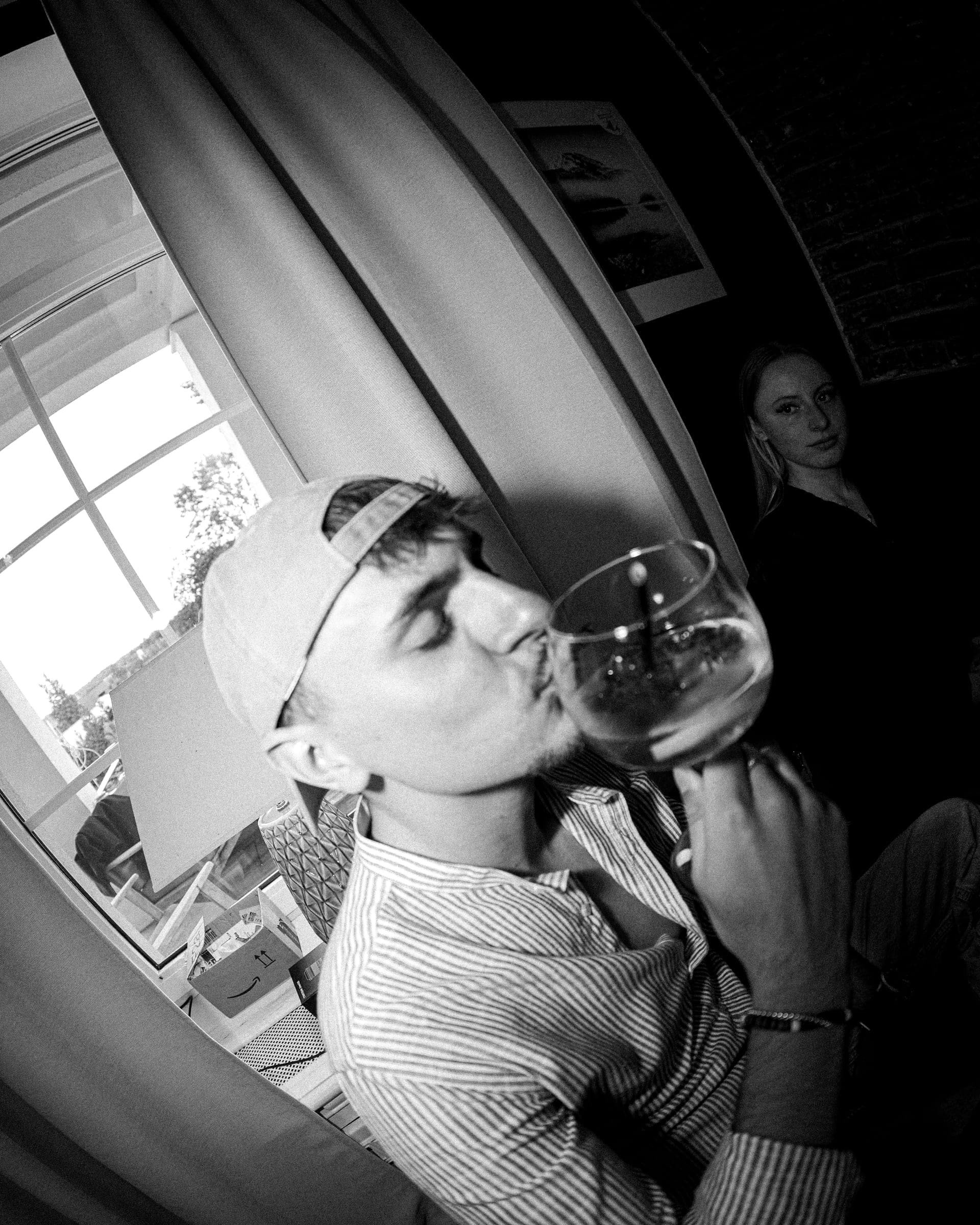 Ein Gast mit Kappe am Fenster der Villa Medici, das Glas am Mund