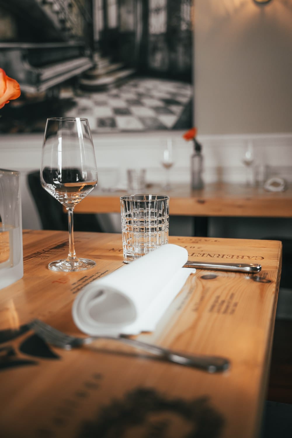 Ein gedeckter Platz mit Weinglas, Wasserglas und gerollter Serviette auf einem Tisch aus Weinkistenholz